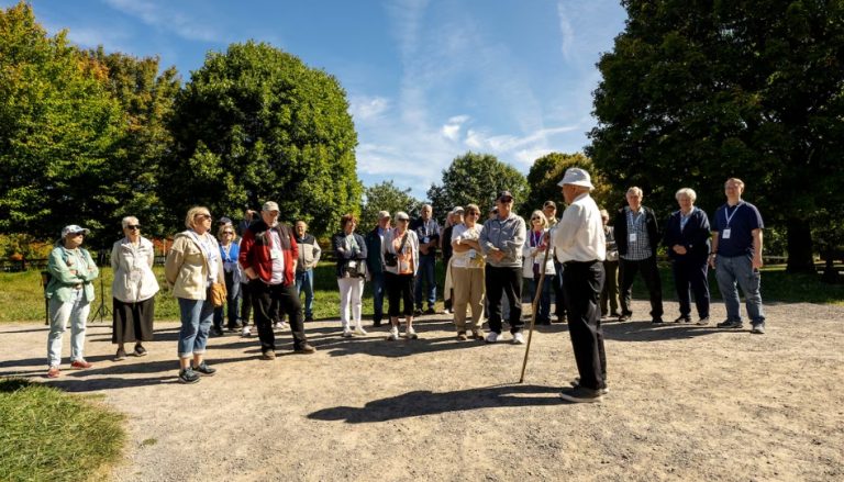 Apoiado em uma bengala, o Élder Bryan Stevens inicia uma visita guiada nos arredores do Centro de Boas-Vindas do Bosque Sagrado em Palmyra, Nova York